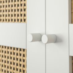 two white cupboards with round knobs on the doors and one has a wicker pattern behind them