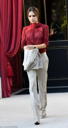 a woman is walking down the street with her hand on her hip and wearing a red blouse