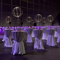 a banquet hall with tables and chairs covered in white tablecloths, lights and decorations