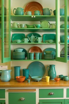 green and yellow dishes are sitting on the shelves in this kitchen, along with plates