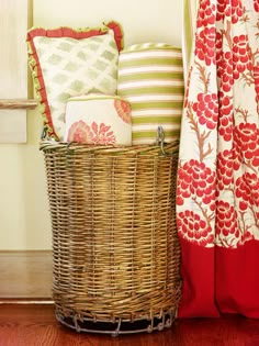 a wicker basket sitting next to a window with red and white pillows in it