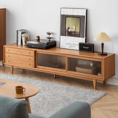 a living room with an entertainment center, coffee table and lamp on the sideboard