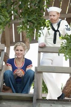 a man and woman dressed in sailor attire standing on a wooden platform next to each other