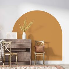 two chairs and a desk in front of a wall with an orange circle painted on it