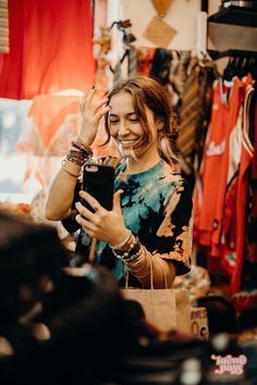 a woman is looking at her cell phone in a clothing store while shopping for clothes