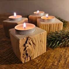 four lit candles sitting on top of wooden blocks