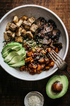 an avocado, tofu and other food items in a bowl on a wooden table