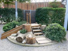 an outdoor play area with logs, rocks and climbing equipment in the middle of it