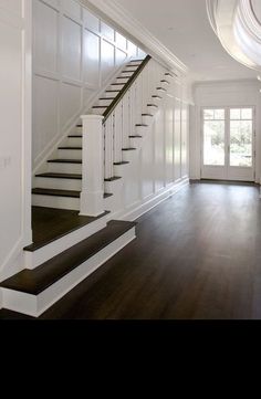 an empty room with white walls and wood floors is pictured in this image, there are stairs leading up to the second floor