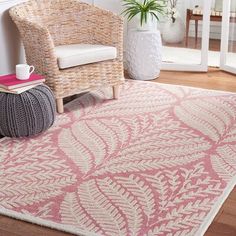 a pink and white area rug in a living room with a wicker chair next to it