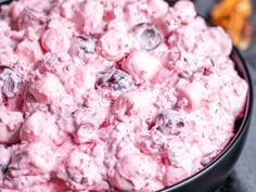 a black bowl filled with blueberries and cream on top of a gray tablecloth