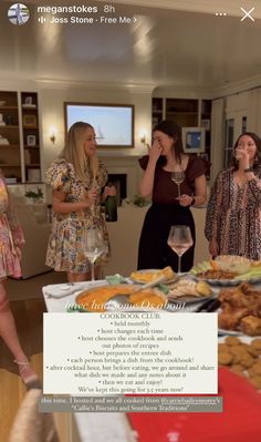 three women standing in front of a table with food and drinks on it, talking to each other