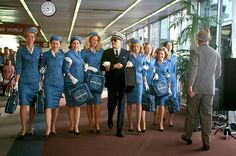 a group of women in blue uniforms standing next to each other with their luggage bags