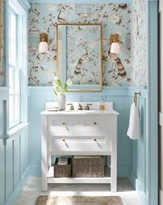 a bathroom with blue walls and a white vanity topped with a mirror next to a window