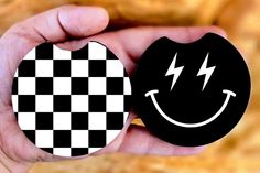 a hand holding two black and white magnets with a smile on one side and a lightning bolt on the other