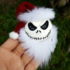 a hand holding a toy with a santa hat and skull face on it's head