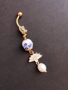 a blue and white beaded belly ring on a black surface with gold fittings