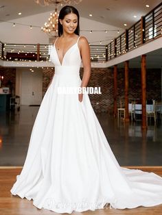 a woman in a white wedding dress standing on a wooden floor with chandelier