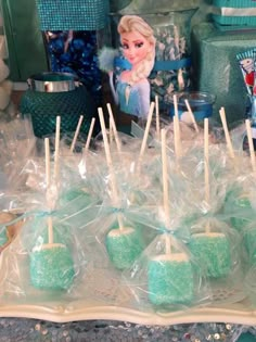 there are many green candies wrapped in plastic and sitting on a tray with toothpicks