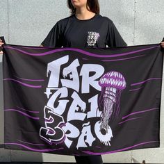 a woman holding up a purple and black banner with a jellyfish design on it