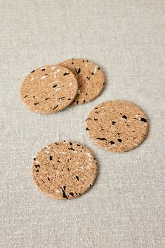 three cork coasters with black speckles on them sitting on a beige surface