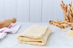 some bread is sitting on a table next to rolling pins and other food items in the background