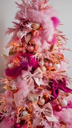 a pink christmas tree decorated with ornaments and feathers, including balls, bows, and baubies