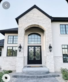 a large white house with black doors and windows on the front door is pictured in this image