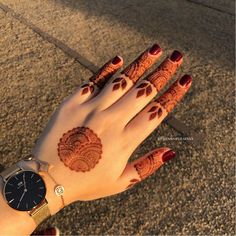 a woman's hand with henna tattoos on it and a watch around her wrist