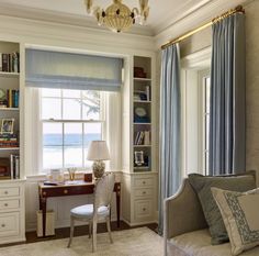 a living room filled with furniture and a window covered in blue drapes next to a desk