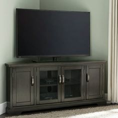 a flat screen tv sitting on top of a wooden entertainment center next to a window