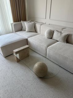 a living room with a white couch and some pillows on the floor next to a glass coffee table