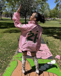 a woman in pink jacket standing on sidewalk next to chalk drawing with numbers painted on it