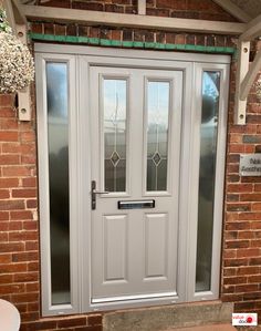 a white front door with glass panels on the side and brick wall in the background