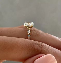 a woman's hand holding an engagement ring with two diamonds on it and the band is