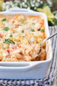 a white casserole dish filled with macaroni and cheese, garnished with parsley