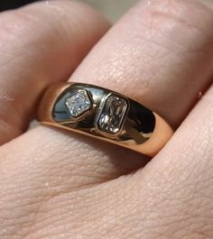 a close up of a person's hand wearing a ring with two diamonds on it