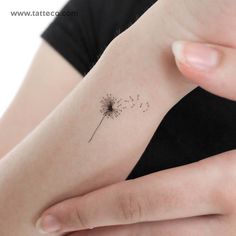 a woman's arm with a dandelion tattoo on the left side of her arm