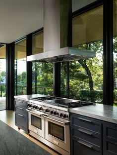 a modern kitchen with stainless steel appliances and large windows looking out onto the trees outside