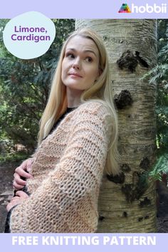 a woman standing next to a tree wearing a knitted sweater