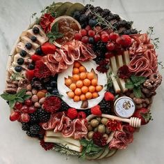 an arrangement of fruits and meats arranged in a circle