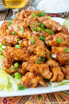 chicken with sauce and green onions on a white plate