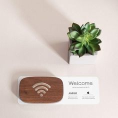 a welcome sign next to a small potted plant on a table with a wifi card