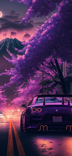 two cars are driving down the road in front of trees with purple flowers on them