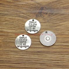 three metal tags with words on them sitting on top of a wooden table next to each other