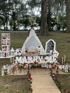 an outdoor wedding setup with candles, flowers and decorations on the ground in front of a teepee tent