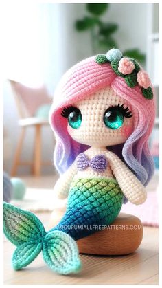 a crocheted mermaid doll sitting on top of a wooden table