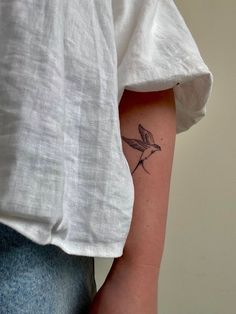 a small hummingbird tattoo on the left arm