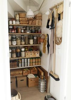 an organized pantry with lots of items on the shelves and hanging utensils in baskets