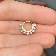 a person is holding a gold ring with small white stones on the inside of it